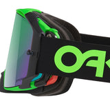 Close-up of Oakley Airbrake motocross goggles with a black and neon green frame, a mirrored purple-to-green lens, and a black strap featuring a large neon green Oakley logo.